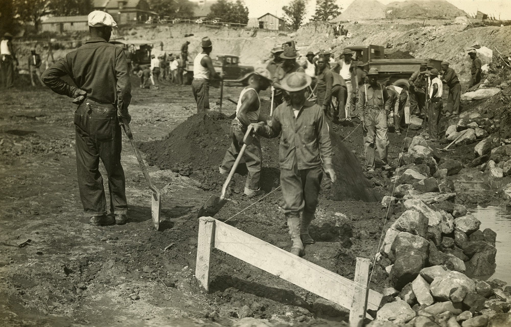 African American workers with hand tools excavate ground for dam